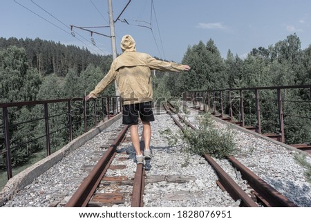 a man walks across an abandoned railway bridge. old iron bridge in the forest across the road.
