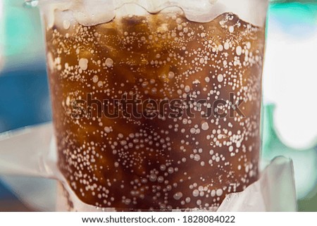 Selective focus of aerated soft drink with ice in plastic glass