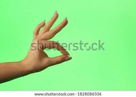 OK gesture on a green background, chromakey, female hand