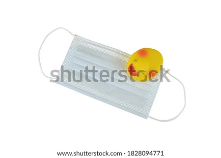 Yellow rubber duck toy with protective medical mask isolated on a white background, coronavirus and respiratory disease preventive concept 
