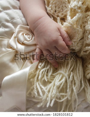 the child's hand lies on a satin fabric with a rose and lace. mother's treasure
