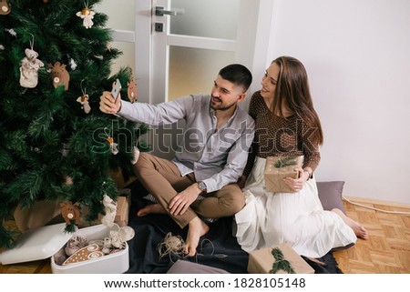 Happy caucasian couple taking pictures with mobile phone and celebrating new year at home