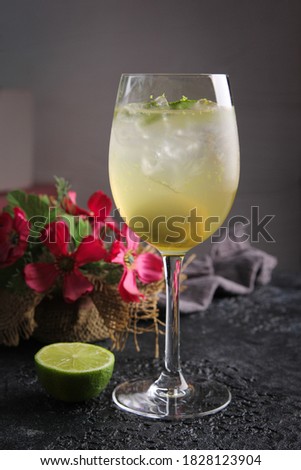 Cocktail. Green drink with lime in a clear glass with ice on a black table. Restaurant menu. Background image, copy space