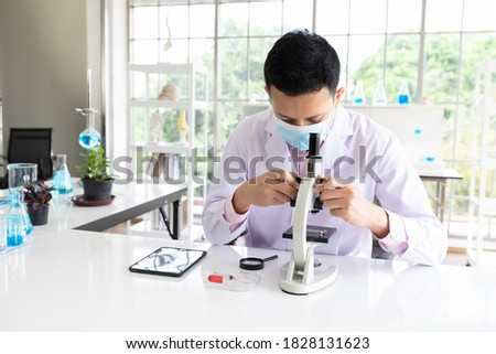 science man wearing medical face mask for protect virus and using microscopes in laboratory