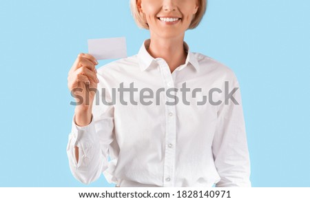Close up of female entrepreneur showing empty business card with space for design over blue studio background, panorama. Smiling female manager holding blank advertising card with mockup