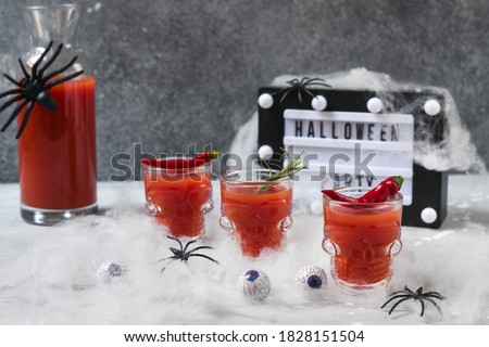 Bloody Mary cocktail or tomato juice in glasses shaped like skulls aperitif Halloween decor cobwebs, spiders and eyes. Day of the dead food , selective focus
