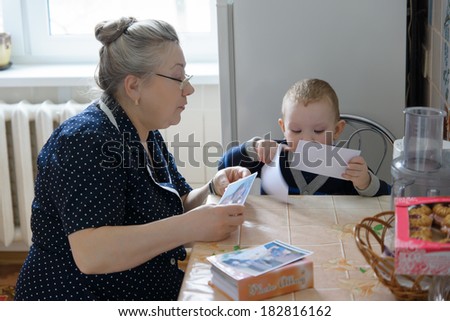 the grandmother with the grandson sit at a table and consider photos