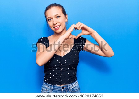 Young blonde woman wearing casual clothes smiling in love doing heart symbol shape with hands. romantic concept. 