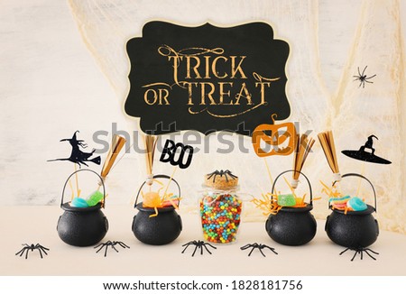 holidays image of Halloween. Witcher cauldron, broom, candies and spiders over white wooden table