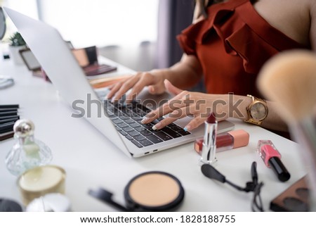 Beautiful young Asian blogger uses a computer on the table. She is shopping for cosmetics online.