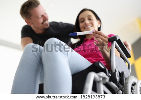 Disabled woman in wheelchair is holding test with her husband at home. Pregnancy and childbirth disabled women concept.