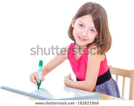 Schoolgirl is sitting at table with pencils, paints.Isolated on white background.