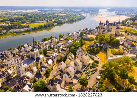 Scenic aerial view of Saumur town on banks of Loire in western France overlooking ancient castle and parish church in summer.. Royalty-Free Stock Photo #1828227623