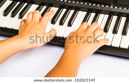 Children hands playing musical keyboard.