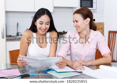 Woman rejoicing at good marks of her teenage daughter in kitchen Royalty-Free Stock Photo #1828235855
