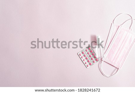 Pink medicine, antibacterial spray and pink face masks on pink background flat lay