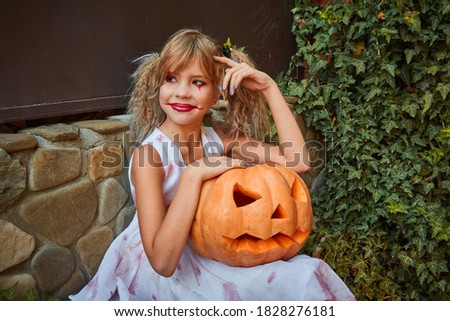 One girl aged 9 in a white dress at a Halloween party with a pumpkin outdoors in the Park. The concept of a fabulous autumn Halloween holiday