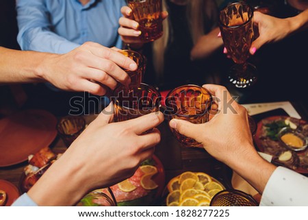 Close up shot of group of people clinking glasses with wine or champagne in front of bokeh background. older people hands.