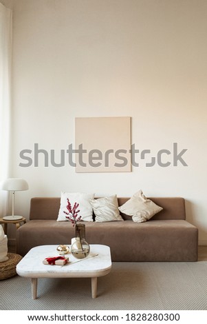 Comfortable modern interior design concept. Sofa, coffee table with decorations, lamp, blank picture frame on the wall. 