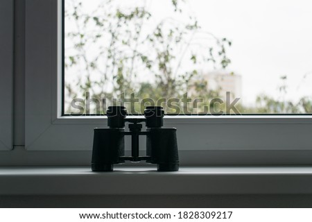 The main subject is out of focus, binoculars stand next to window voyeurism Mental Health Disorders spy on neighbors people concept Royalty-Free Stock Photo #1828309217