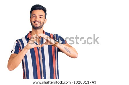 Young handsome hispanic man wearing casual  summer shirt smiling in love showing heart symbol and shape with hands. romantic concept. 