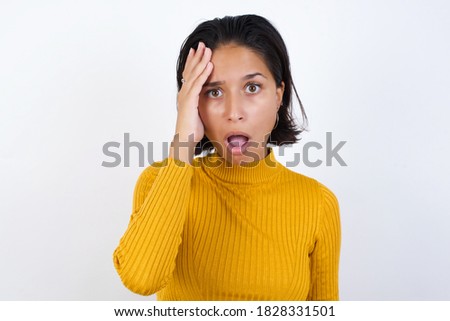 Embarrassed Young woman with short hair wearing casual yellow sweater isolated over white background, with shocked expression, expresses great amazement, Puzzled man poses indoor