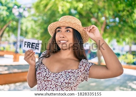 Young latin woman on vacation holding free word paper walking at street of city.