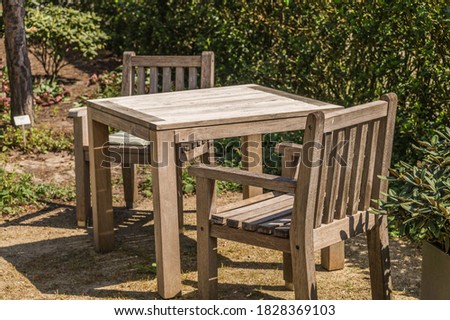 Wooden table with two chairs in garden on a summer day.
