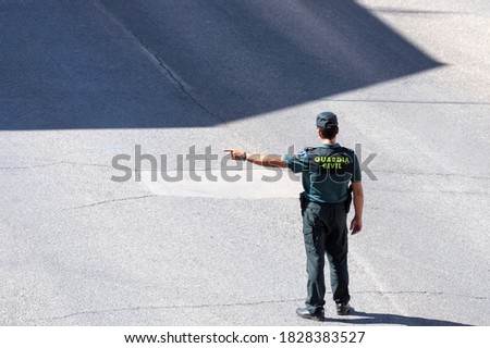 A Spanish Civil Guard points out the direction of traffic Royalty-Free Stock Photo #1828383527