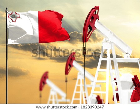 Oil rigs against the backdrop of the colorful sky and a flagpole with the flag of Malta. The concept of oil production, minerals, development of new deposits.
