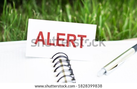 text alert on desktop on a white business card on a notepad and a pen. Business concept