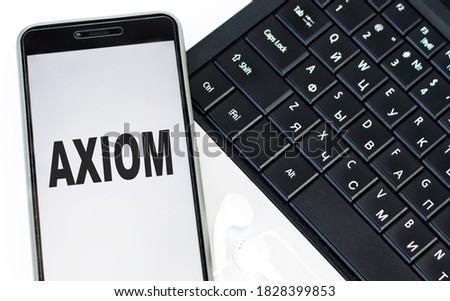 AXIOM word on the phone screen that lies on the laptop keyboard