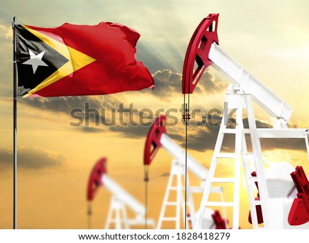 Oil rigs against the backdrop of the colorful sky and a flagpole with the flag of East Timor. The concept of oil production, minerals, development of new deposits.