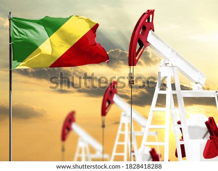 Oil rigs against the backdrop of the colorful sky and a flagpole with the flag of Congo,Republic. The concept of oil production, minerals, development of new deposits.