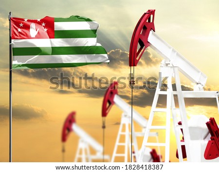 Oil rigs against the backdrop of the colorful sky and a flagpole with the flag of Abkhazia. The concept of oil production, minerals, development of new deposits.