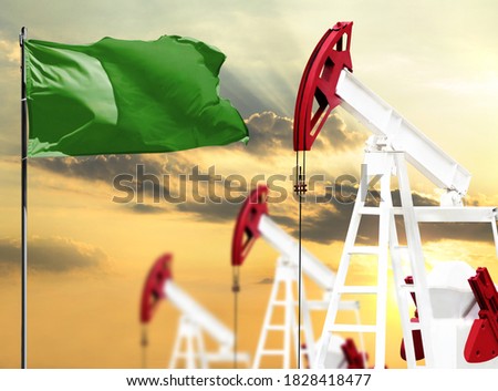 Oil rigs against the backdrop of the colorful sky and a flagpole with the flag of Libya. The concept of oil production, minerals, development of new deposits.