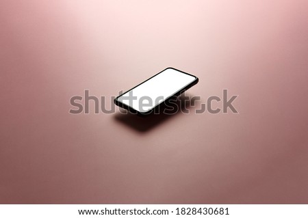 A minimalistic mock up flat image design with a floating mobile phone with copy space and white scree to write over it over a flat pastel pink background