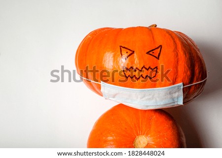 Top view of an evil bright orange pumpkin in a medical mask. Coronavirus pandemic concept, Halloween. Flat lay, space for text.