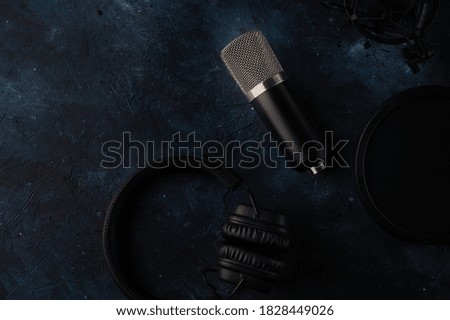 Headphone and studio microphone with shock mount and pop filter on dark blue background. Music concept. Recording studio.