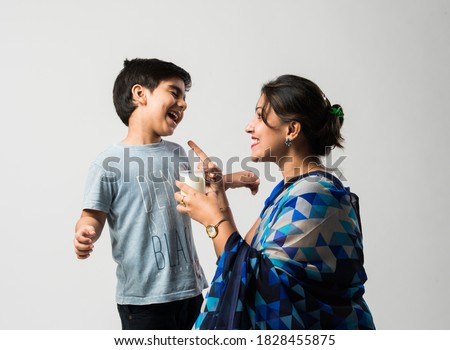 Indian pretty mother making her son drink milk in a glass Royalty-Free Stock Photo #1828455875