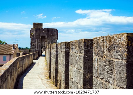 Walking along defensive antique walls of the medieval port city of Aigues-Mortes. Sunny summer day. Mediterranean coast of France. The concept of active, historical and photo tourism