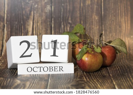 October 21. Day 21 of month. Calendar cube on wooden background with red apples, concept of business and an important event. Autumn season.