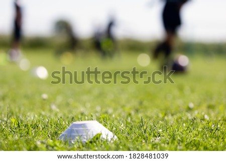 Blurred background of training soccer field. Sports soccer grass venue. Training football marker on the grass field. Running footballers in blurred background