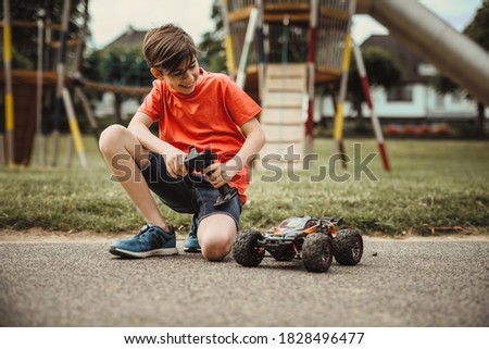 teen boy with electric remote control car toy play outdoor on sidewalk and have fun while enjoy his childhood Royalty-Free Stock Photo #1828496477