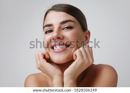Close-up portrait of young pretty woman, she is smiling and posing in the studio. Isolates on white wall.