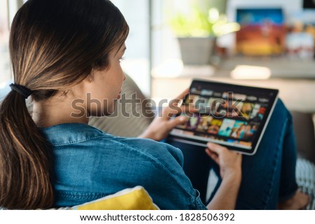 Woman Choosing Movie For Streaming On Tablet Computer