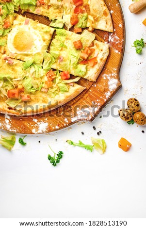 Pizza with bacon meat, egg yolk and green salad on the wooden plate and white background