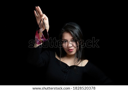 Young woman with mask in hand with dark background Royalty-Free Stock Photo #1828520378