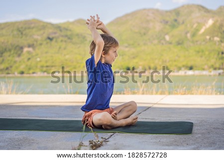 Boy doing yoga on a yoga mat against a background of mountains