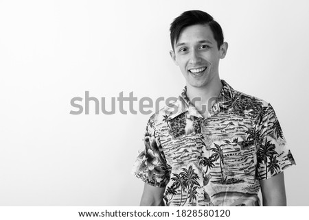 Studio shot of young happy tourist man smiling against white background